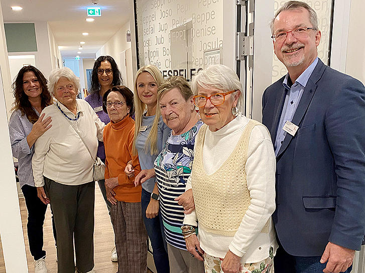 Einrichtungsleiter Sven Lefkowitz (rechts) öffnet symbolisch die Tür mit dem Team der Tagespflege und einigen Gästen.