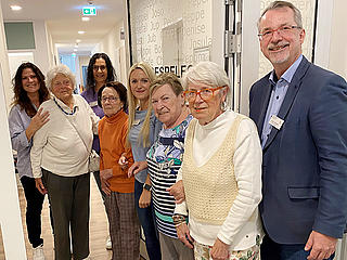 Einrichtungsleiter Sven Lefkowitz (rechts) öffnet symbolisch die Tür mit dem Team der Tagespflege und einigen Gästen.